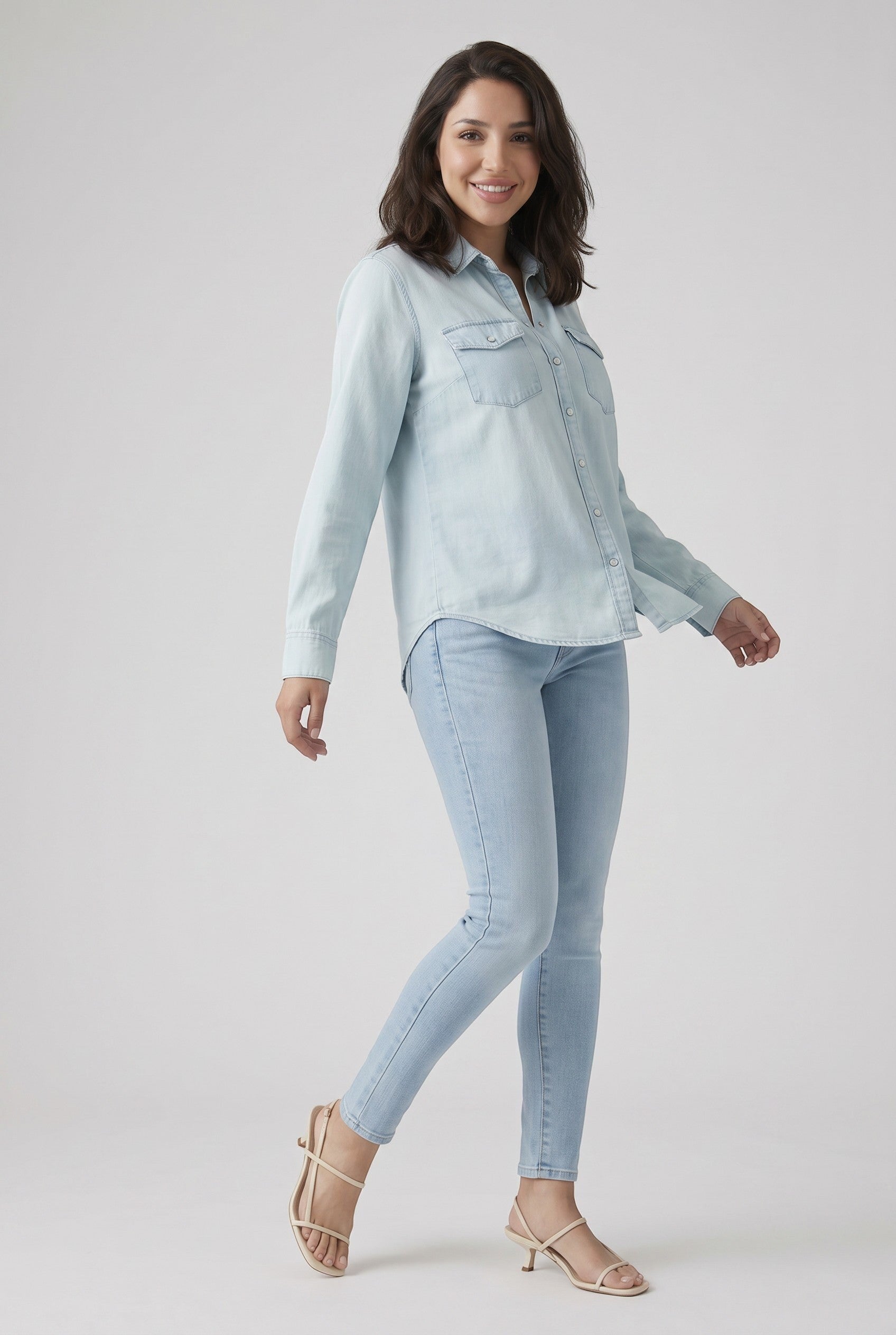 Vella Moda model wearing Levi's 711 light wash skinny jeans and a matching denim shirt with strappy beige heels