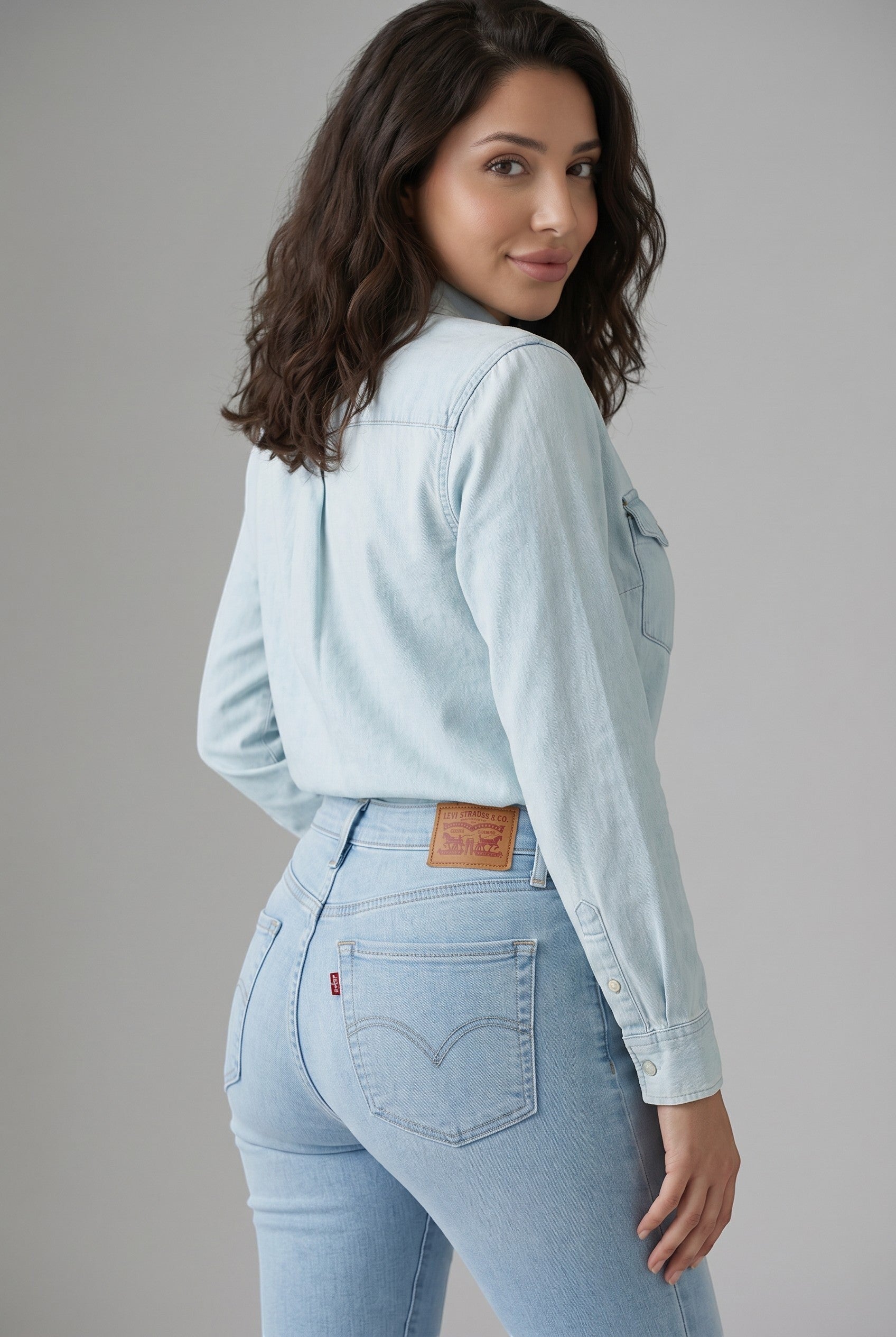 Vella Moda model wearing Levi's 711 light wash skinny jeans and a matching denim shirt from behind