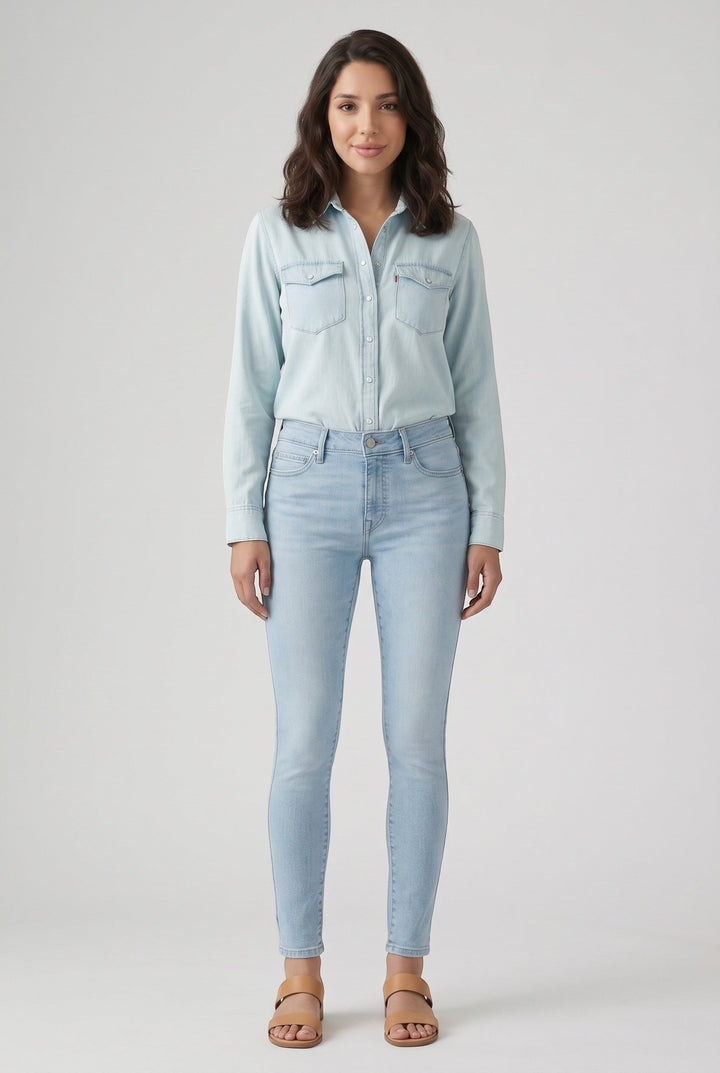 Vella Moda model wearing Levi's 711 light wash skinny jeans and a matching denim shirt with tan sandals