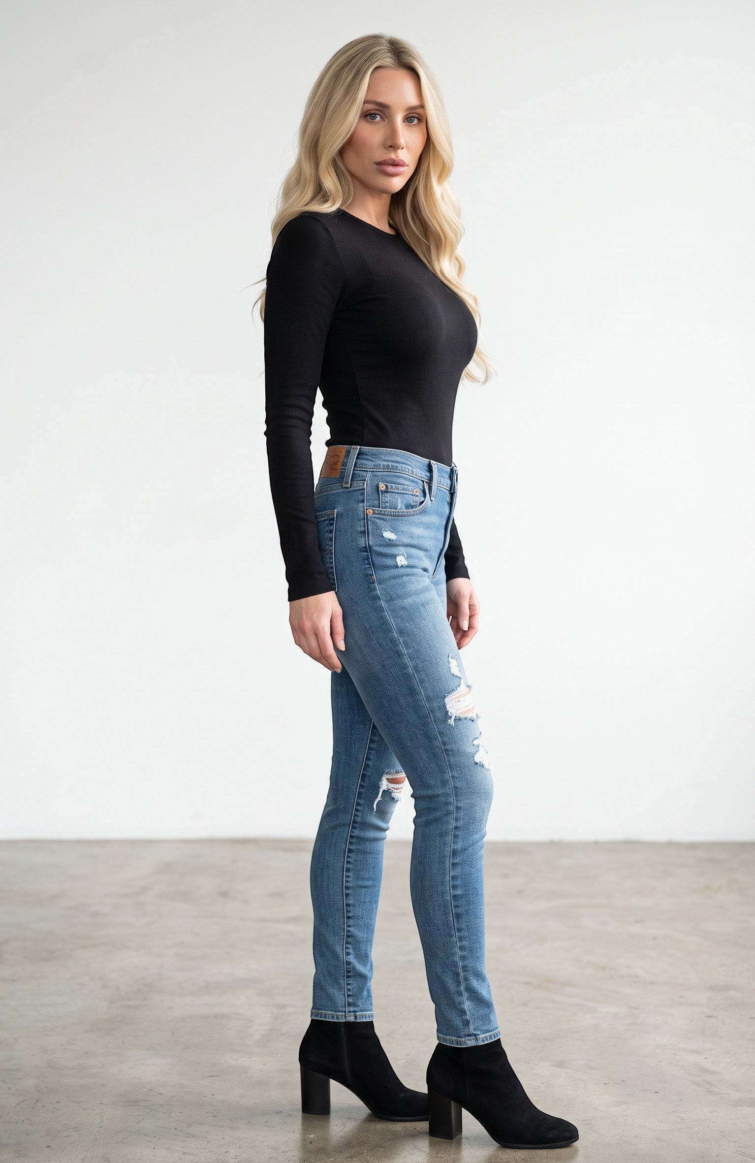 Vella Moda model wearing Levi's 711 mid-rise skinny jeans in medium wash with distressed details and black boots